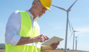 man with ipad next to wind turbine